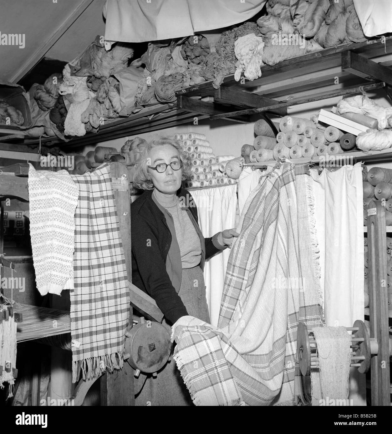 Femme vu ici avec rouleaux de matériau qu'elle a tissé avec son métier. 1955 Banque D'Images
