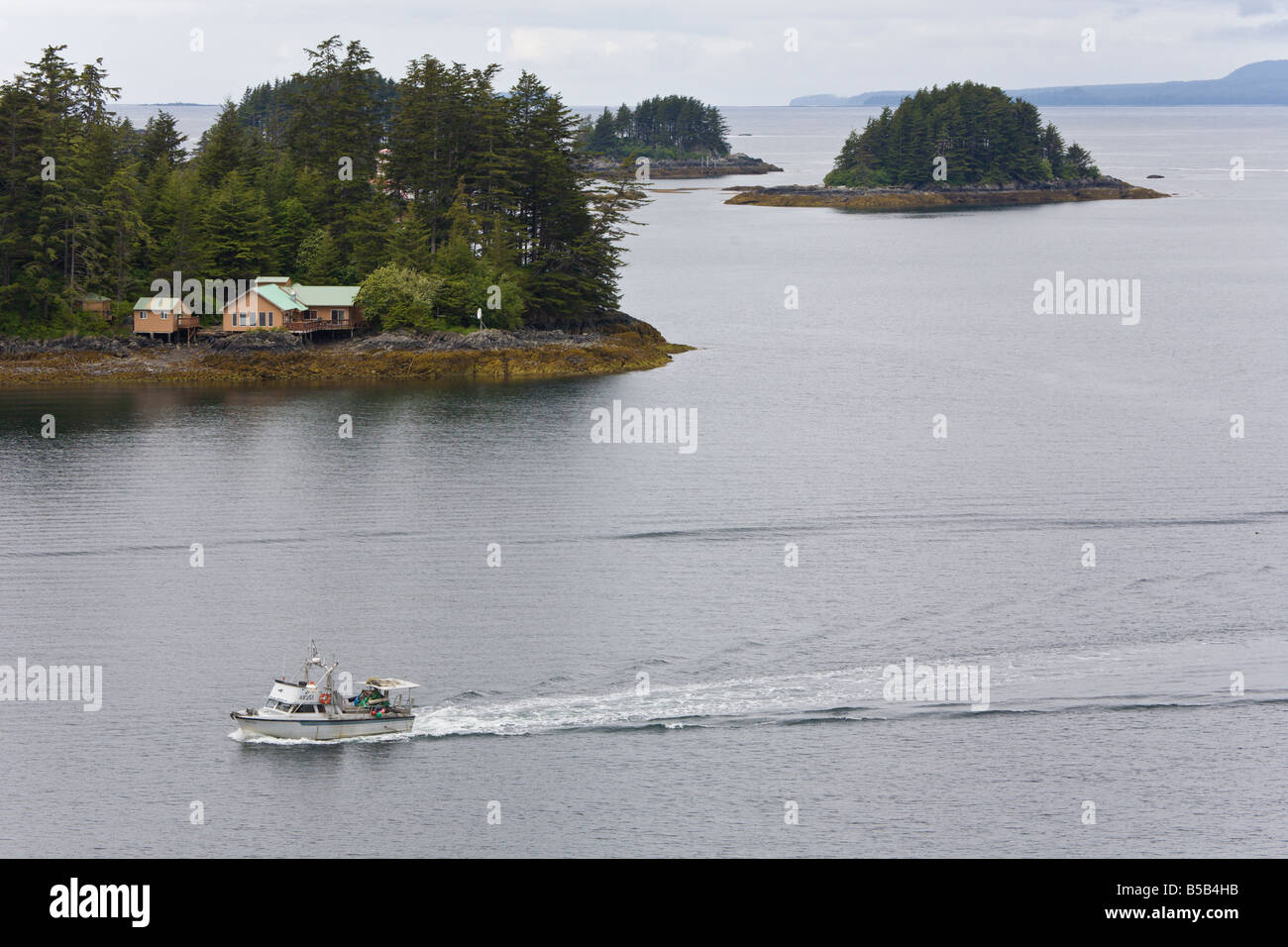 Bateau de pêche commerciale privée permet de naviguer dans le chenal est passé dans les maisons de l'île privée de Sitka, Alaska Banque D'Images