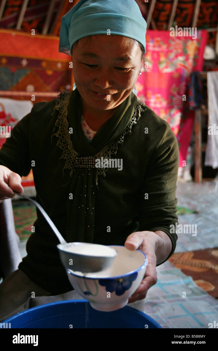 Femme mongole pour kumiss dans une tasse à l'intérieur de la tente de nomades Banque D'Images