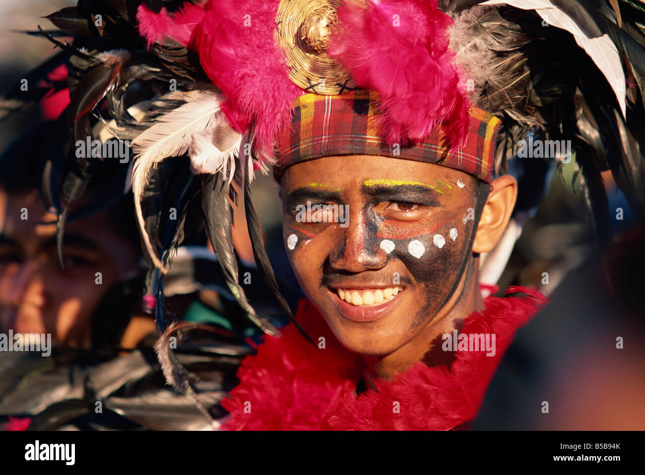 Portrait d'un homme avec la décoration du visage et de la tête avec des plumes robe à Mardi Gras carnival Dinagyang à Iloilo City sur Panay Banque D'Images