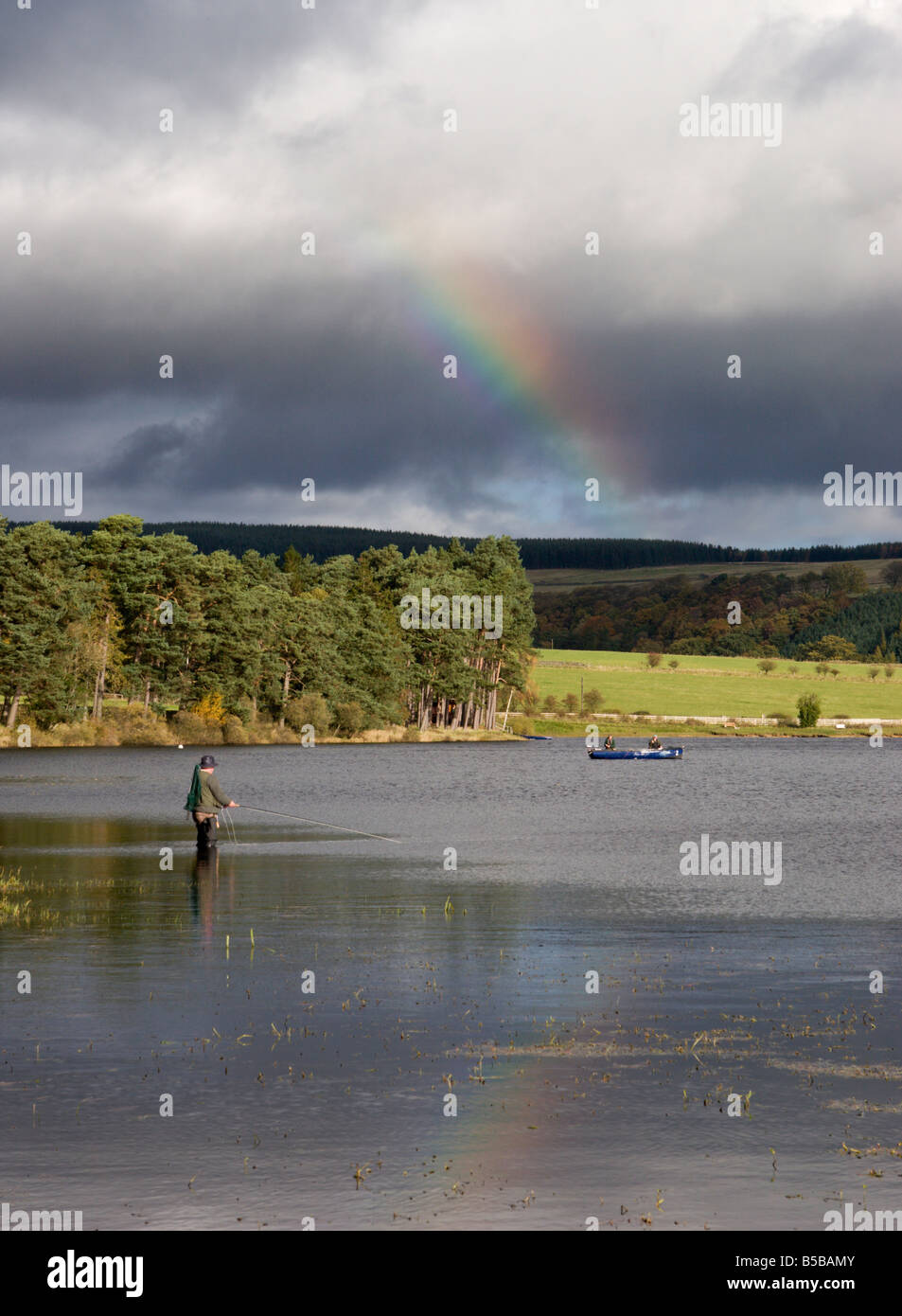 Pêcheur au réservoir Tunstall avec un arc-en-ciel en arrière-plan, dans le comté de Durham, England, UK Banque D'Images