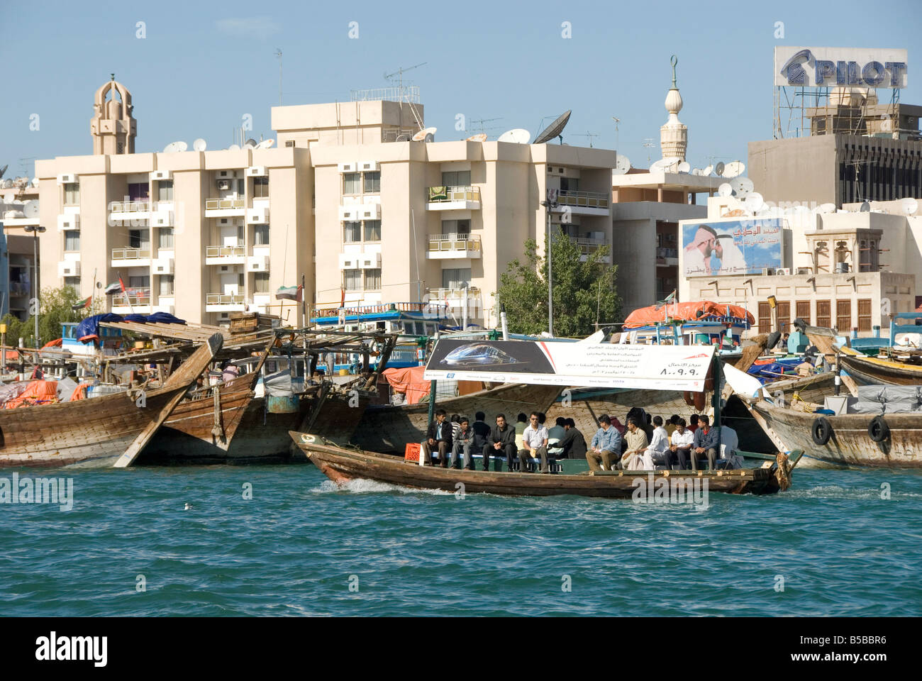 Abra (cross-creek ferry) chugs boutre passé des quais et des édifices modernes de Deira, Dubai Creek, Dubai, Émirats Arabes Unis Banque D'Images