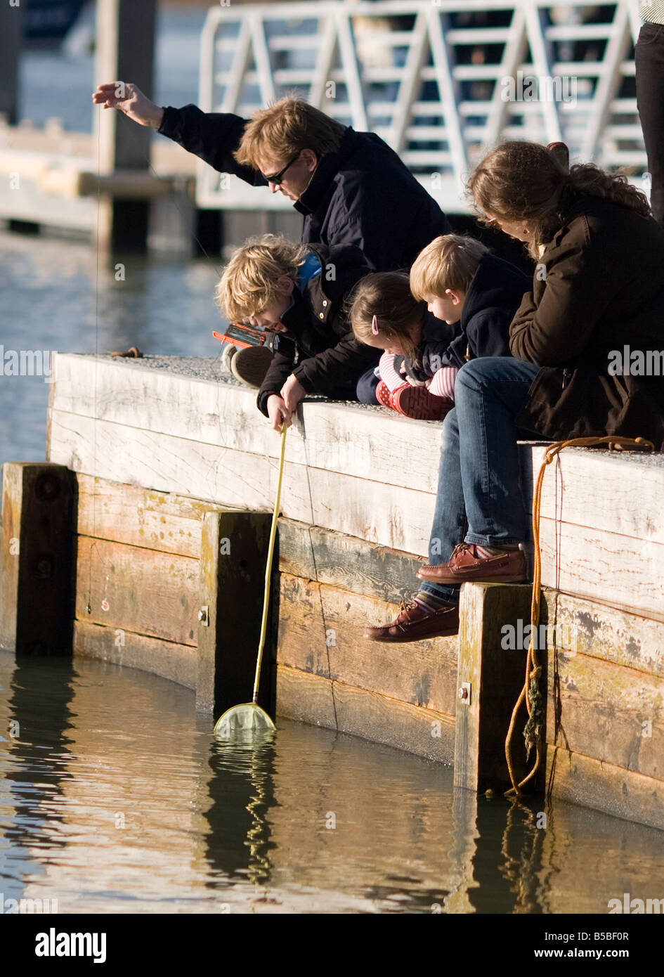 Family sitting on jetty pêche au crabe Banque D'Images