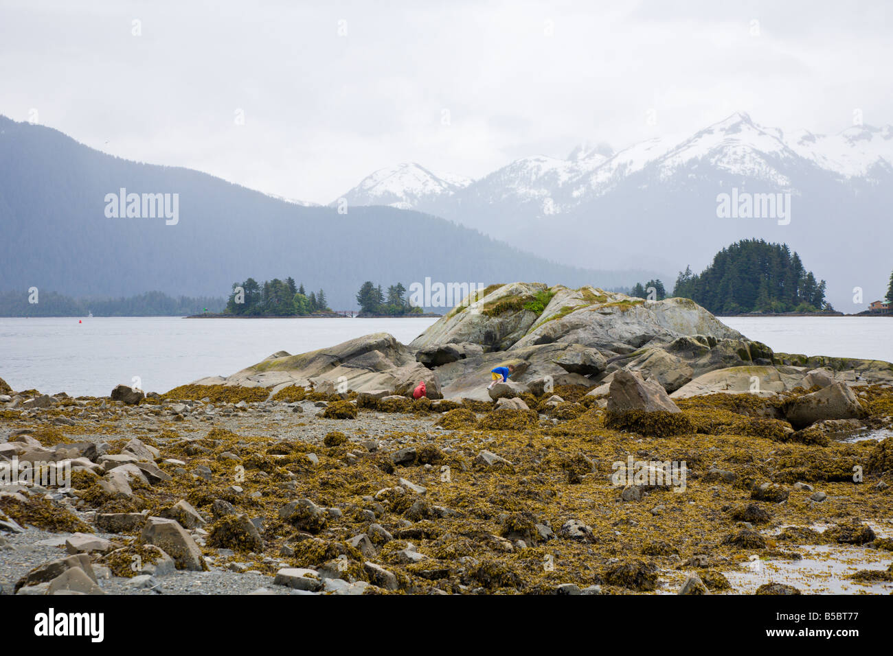 Deux enfants d'escalade sur rochers à la Manche orientale côte à Sitka, Alaska Banque D'Images