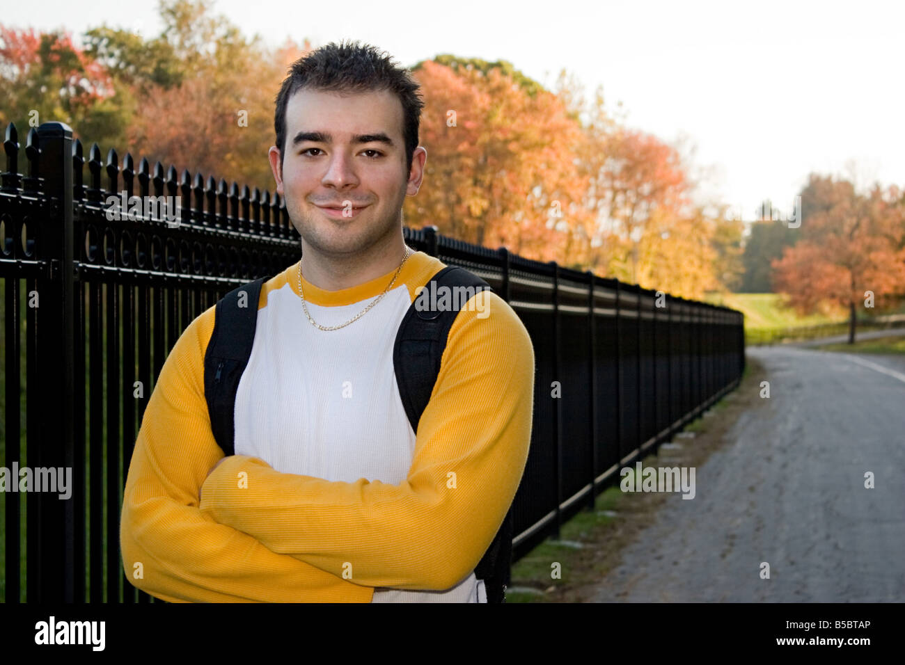 Un jeune étudiant debout sur un campus de l'école avec les bras croisés Banque D'Images