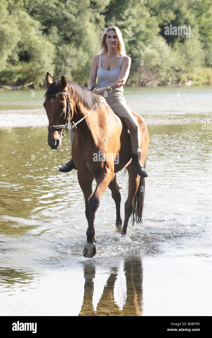 Femme blonde l'équitation dans une rivière, Banque D'Images