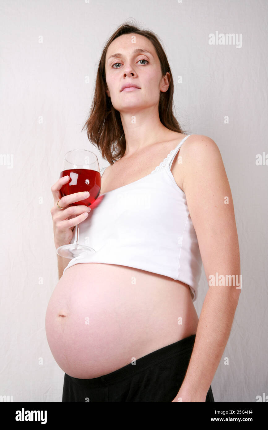 Jeune Femme Enceinte Au Troisieme Trimestre A 32 Semaines De Boire De L Alcool De Vin Rouge Bon Marche Maintenant Dans Grand Verre Debout Photo Stock Alamy