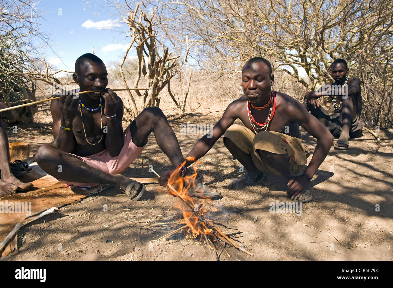 Les hommes Hadza plier une flèche de chasse sur un feu Lake Eyasi Tanzanie Banque D'Images
