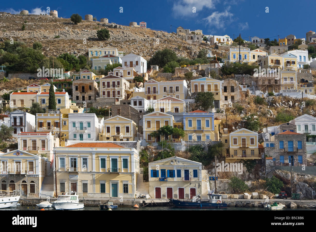Des bateaux et des maisons sur le port pittoresque de Yialos, sur l'île de Symi, Grèce Banque D'Images Des bateaux et des maisons sur le port pittoresque de Yialos, sur l'île de Symi, Grèce Banque D'Images