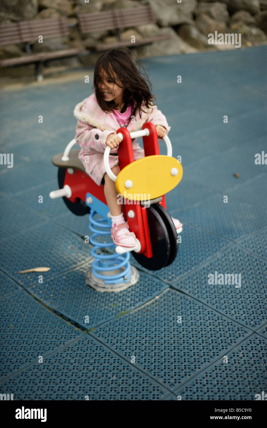 Jeune fille sur moto en jeu pour enfants Banque D'Images