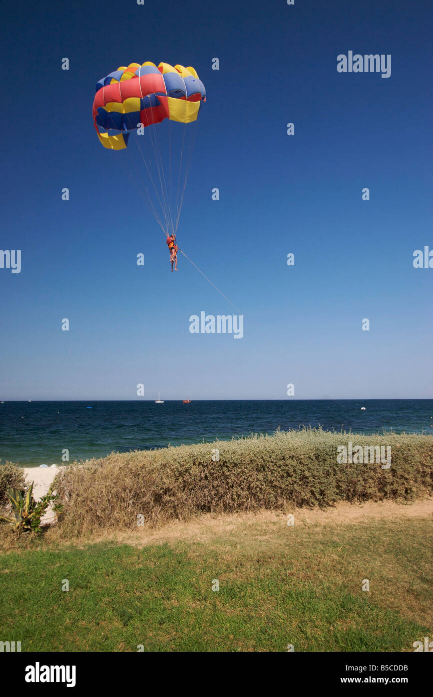 Un parapentiste avec deux passagers en gilets est sur le point d'atterrir sur une plage tunisienne à la mer Méditerranée. Banque D'Images