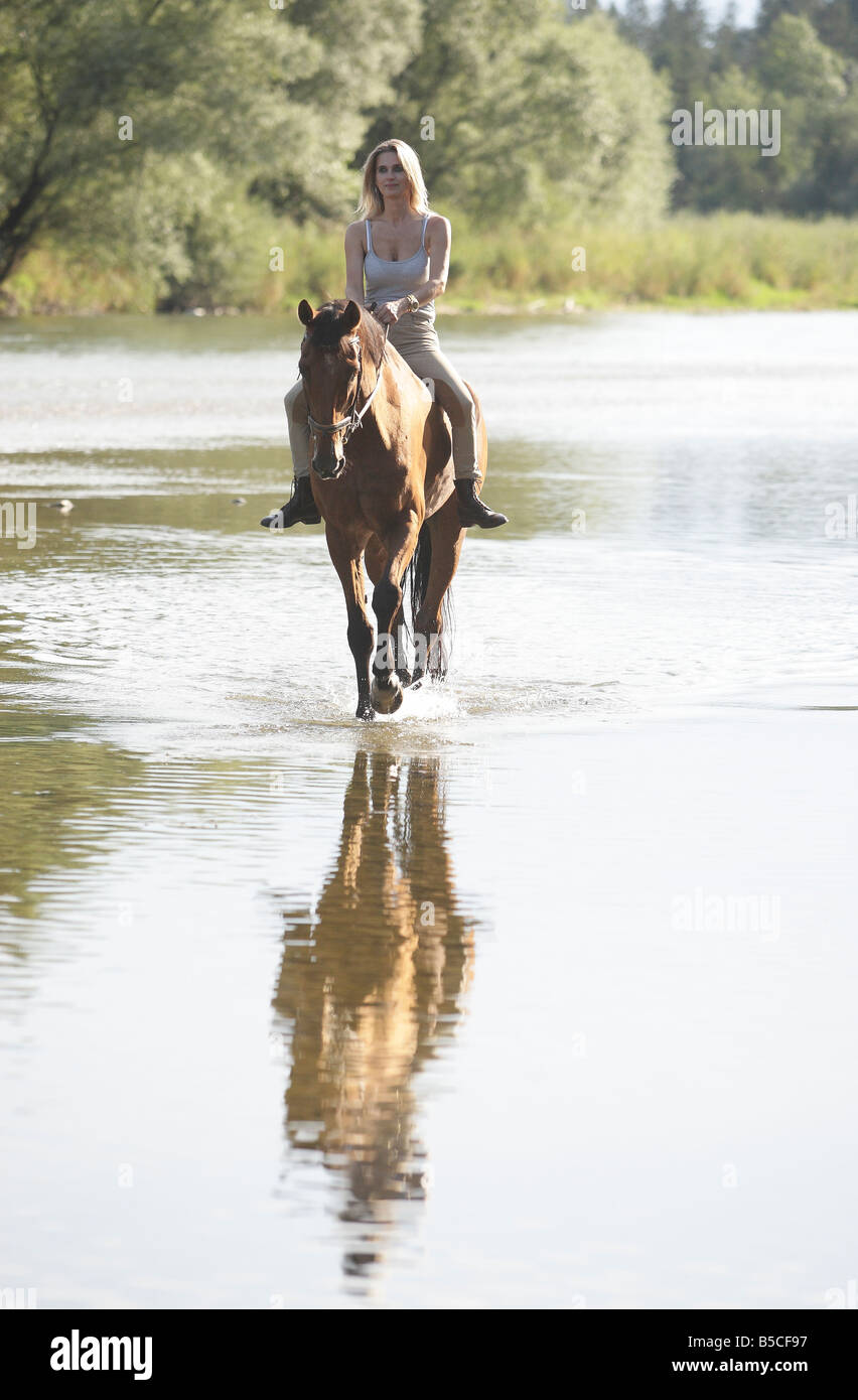 Femme blonde l'équitation dans une rivière, Banque D'Images