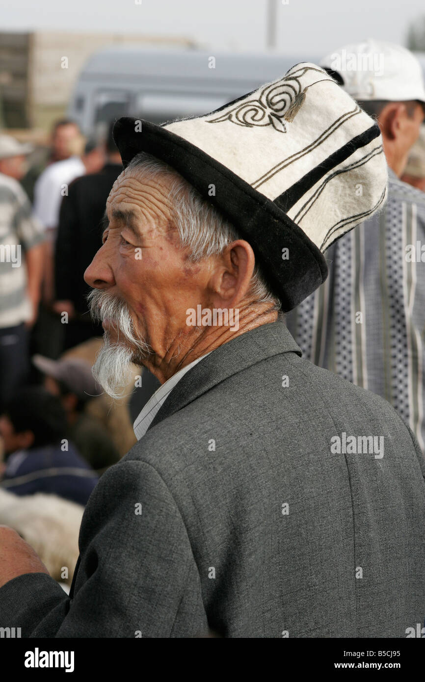 Portrait d'ancien homme portant chapeau traditionnel kirghize (kalpak) le dimanche marché des animaux à Karakol, le Kirghizistan, l'Asie centrale Banque D'Images