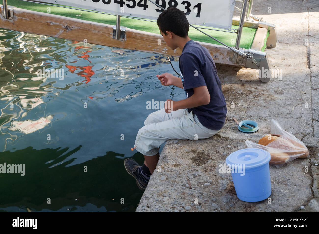 Un jeune garçon turc la pêche dans un port méditerranéen à Fethiye Turquie Banque D'Images