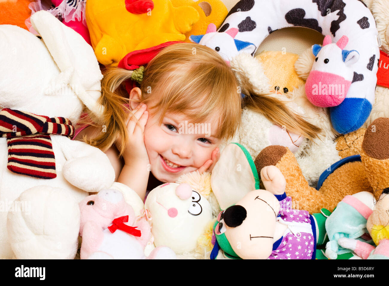 Smiling blonde petite fille, 4 ans, avec des peluches animaux Banque D'Images