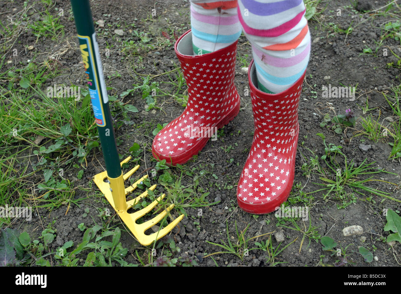 Young Girl wearing red Welly bottes sur un allotissement Banque D'Images