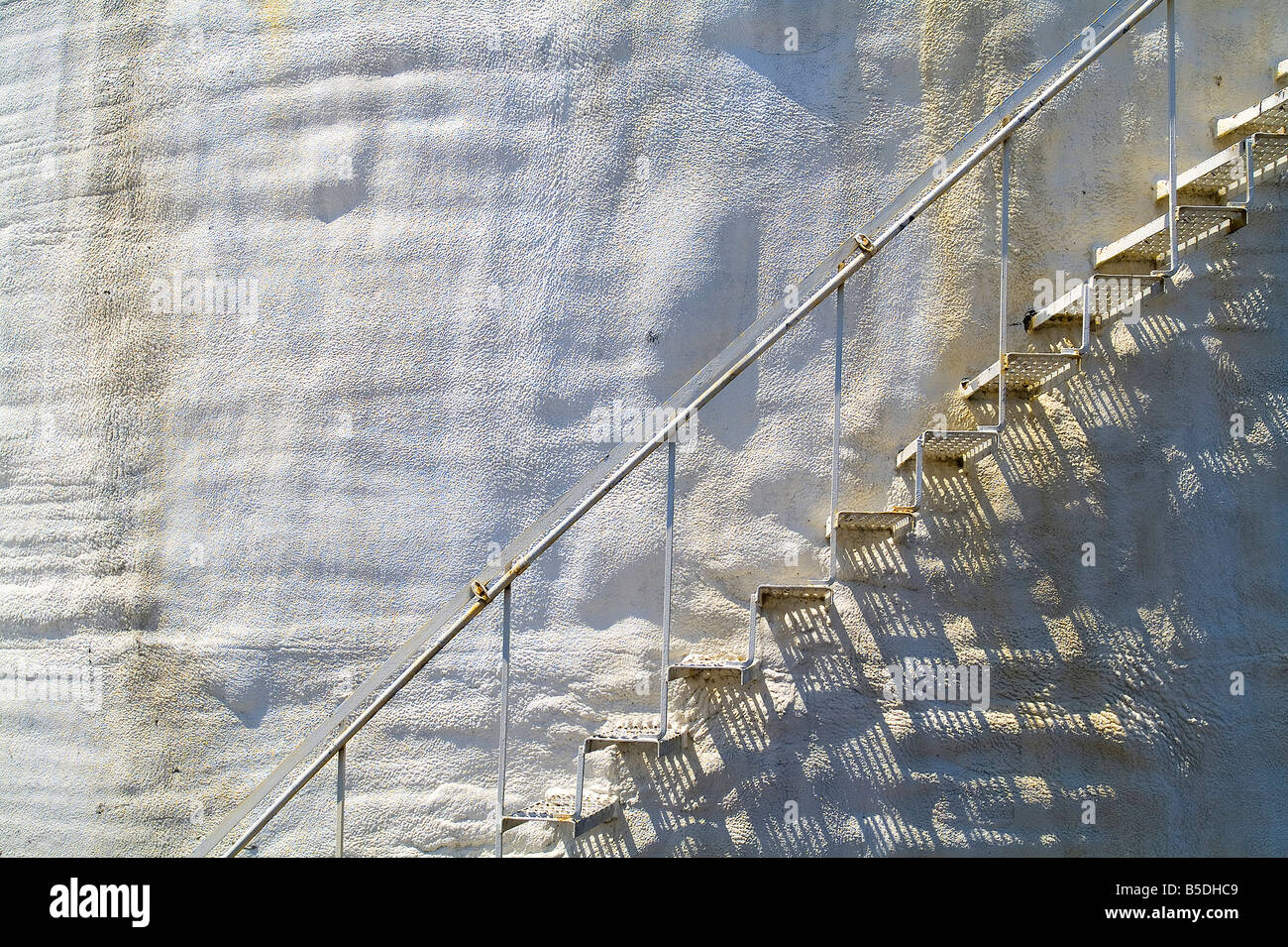 Vieux Escaliers en métal sur le côté du réservoir de stockage en stuc blanc avec des taches de rouille, USA Banque D'Images