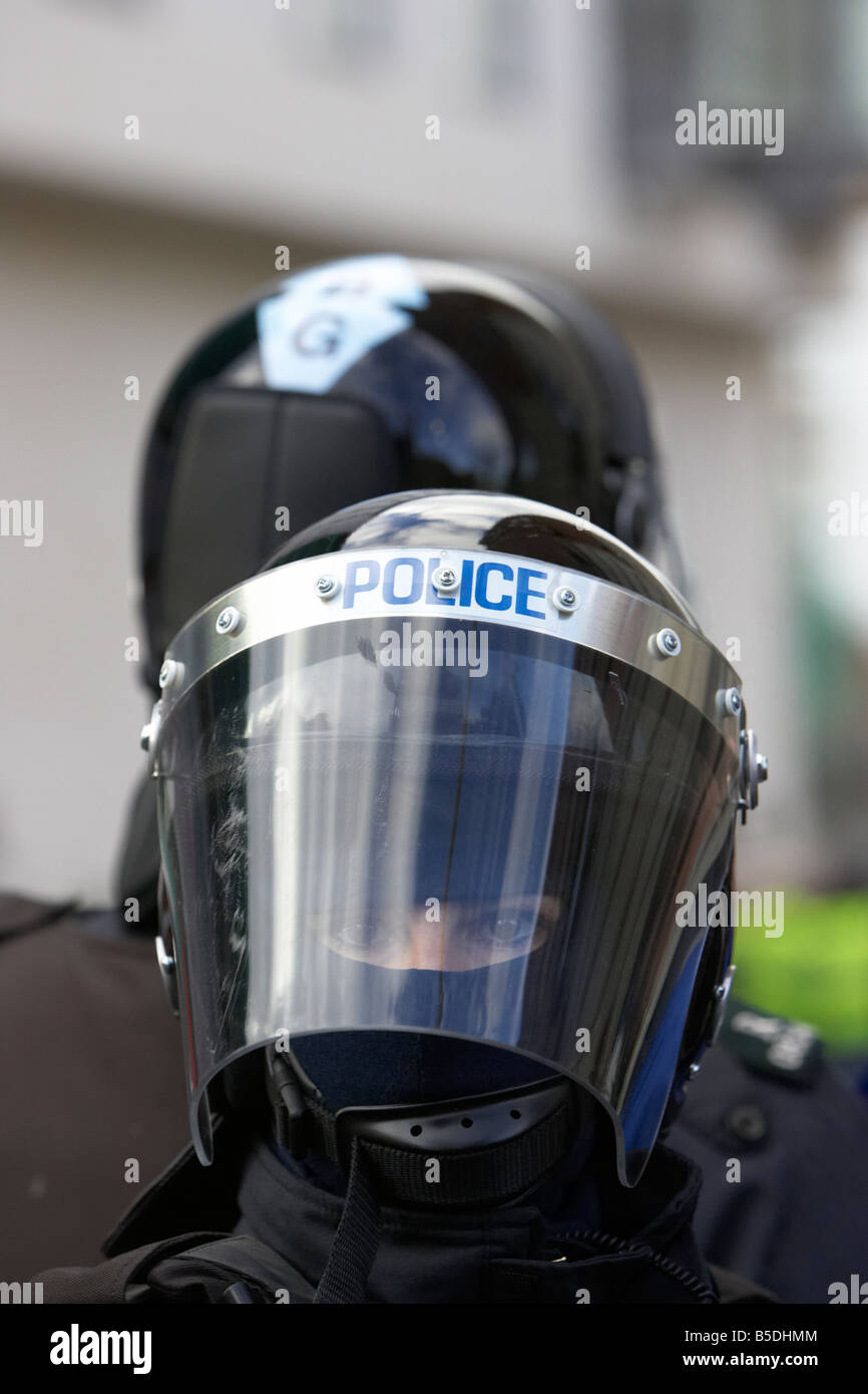 Service de police PSNI de l'Irlande du Nord policière et collègue le port du casque et de la visière anti-émeute à regarder Banque D'Images