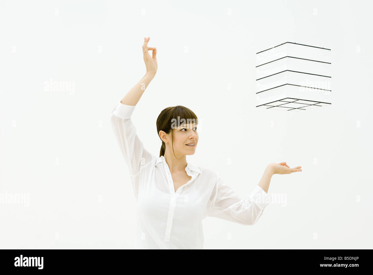 Woman raising arms, regardant en l'air flottant cube Banque D'Images