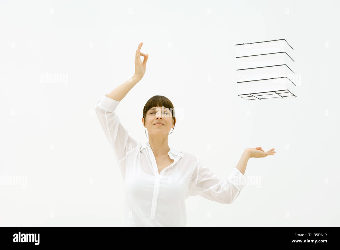 Woman raising arms, yeux clos, cube flottant dans l'air Banque D'Images