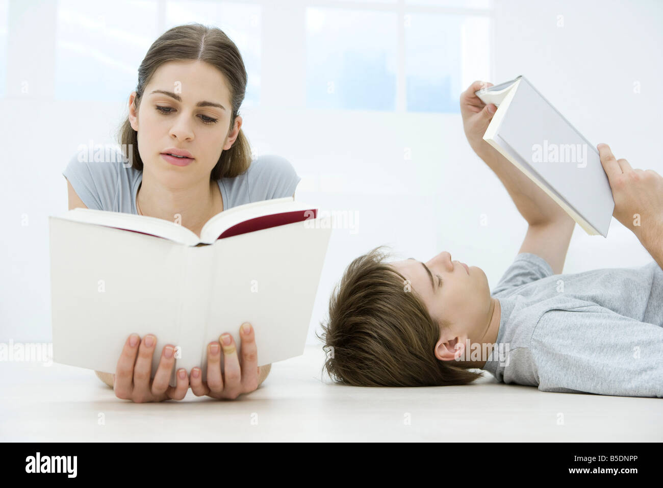 Couple reading books, l'homme allongé sur le dos, woman lying on stomach Banque D'Images