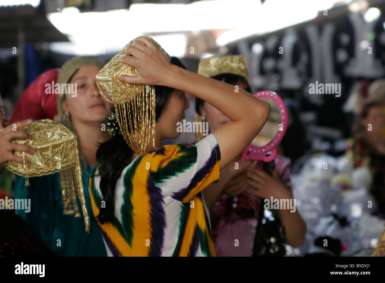 Jeune femme ouzbek essayant sur mariage traditionnel skullcap, marché du dimanche de Urgut, l'Ouzbékistan, en Asie centrale Banque D'Images