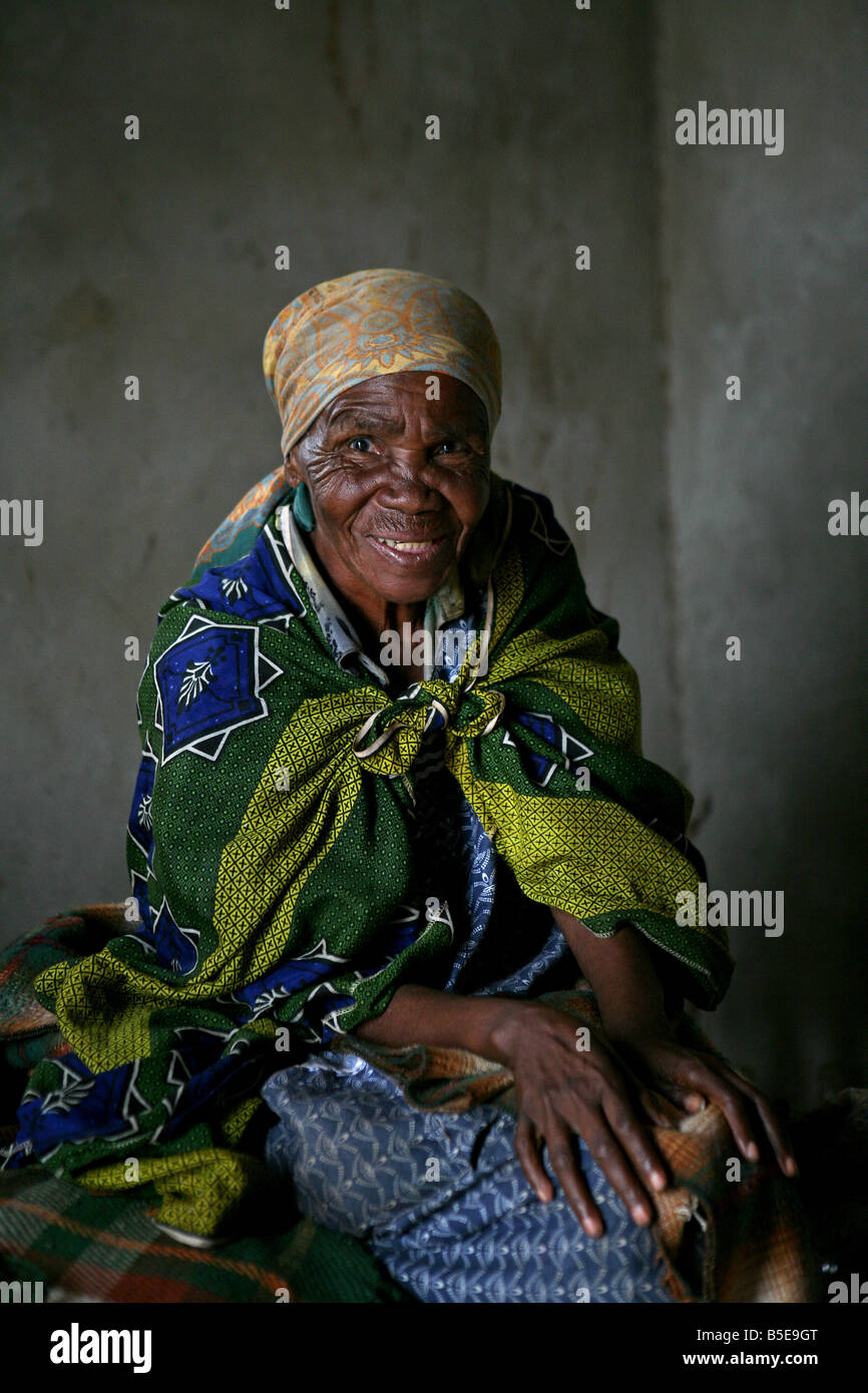 Grand-mère Swazi est assise dans sa maison construite par la Croix-Rouge, de Shiselweni, Swaziland, Afrique Banque D'Images