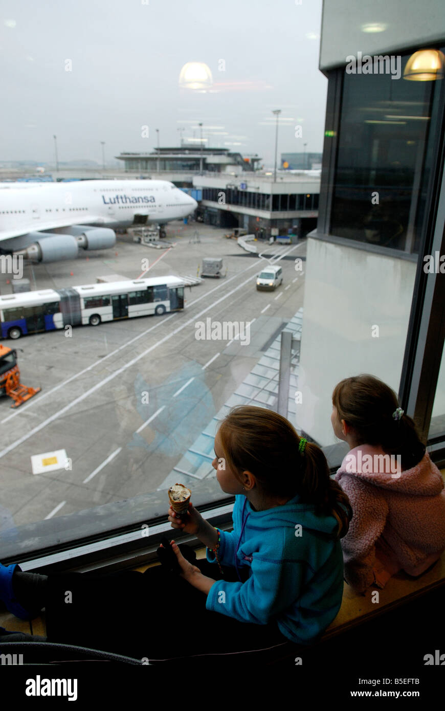 Deux enfants regardant par la fenêtre les avions à l'aéroport de Francfort, Allemagne Banque D'Images