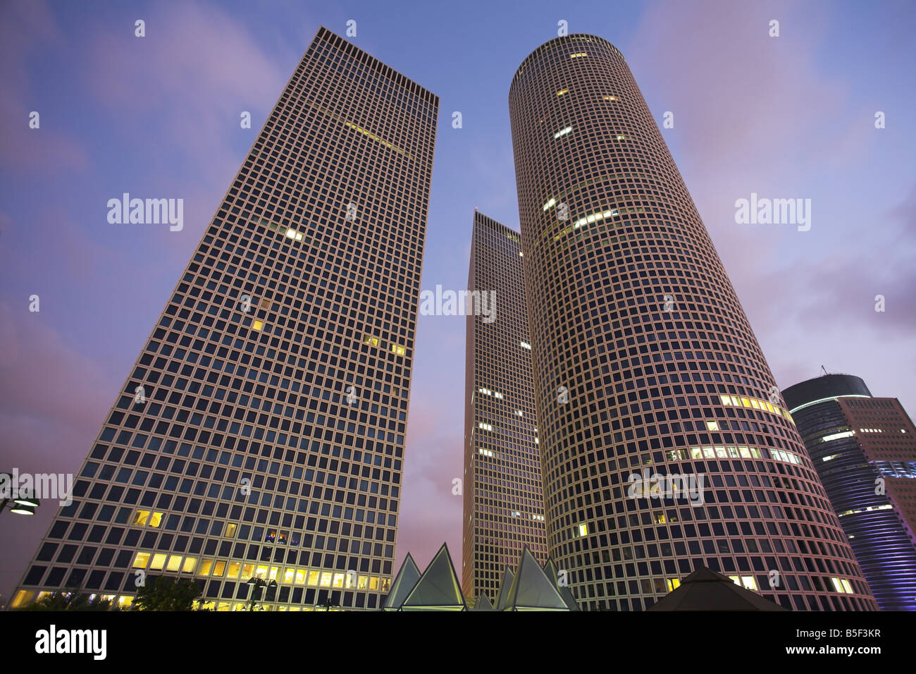 Round square et triangulaires de gratte-ciel dans la partie affaires Tel Aviv sur un coucher de soleil Banque D'Images