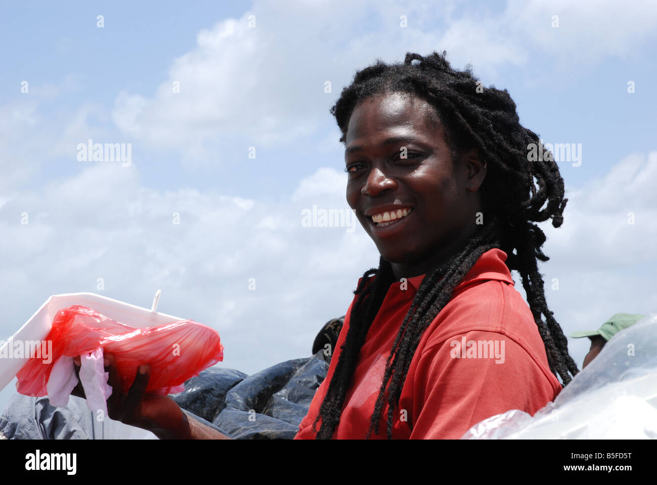 Homme noir rasta sur un canoë smiling with finger food Banque D'Images