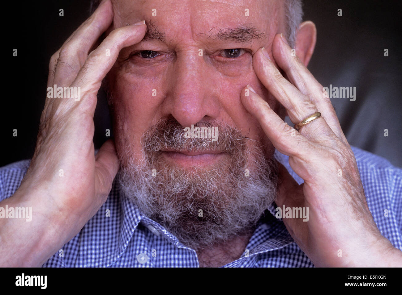 Homme caucasien âgé réfléchissant et inquiet. Seul dans sa chambre, la tête dans les mains. Anxiété de santé et stress Banque D'Images