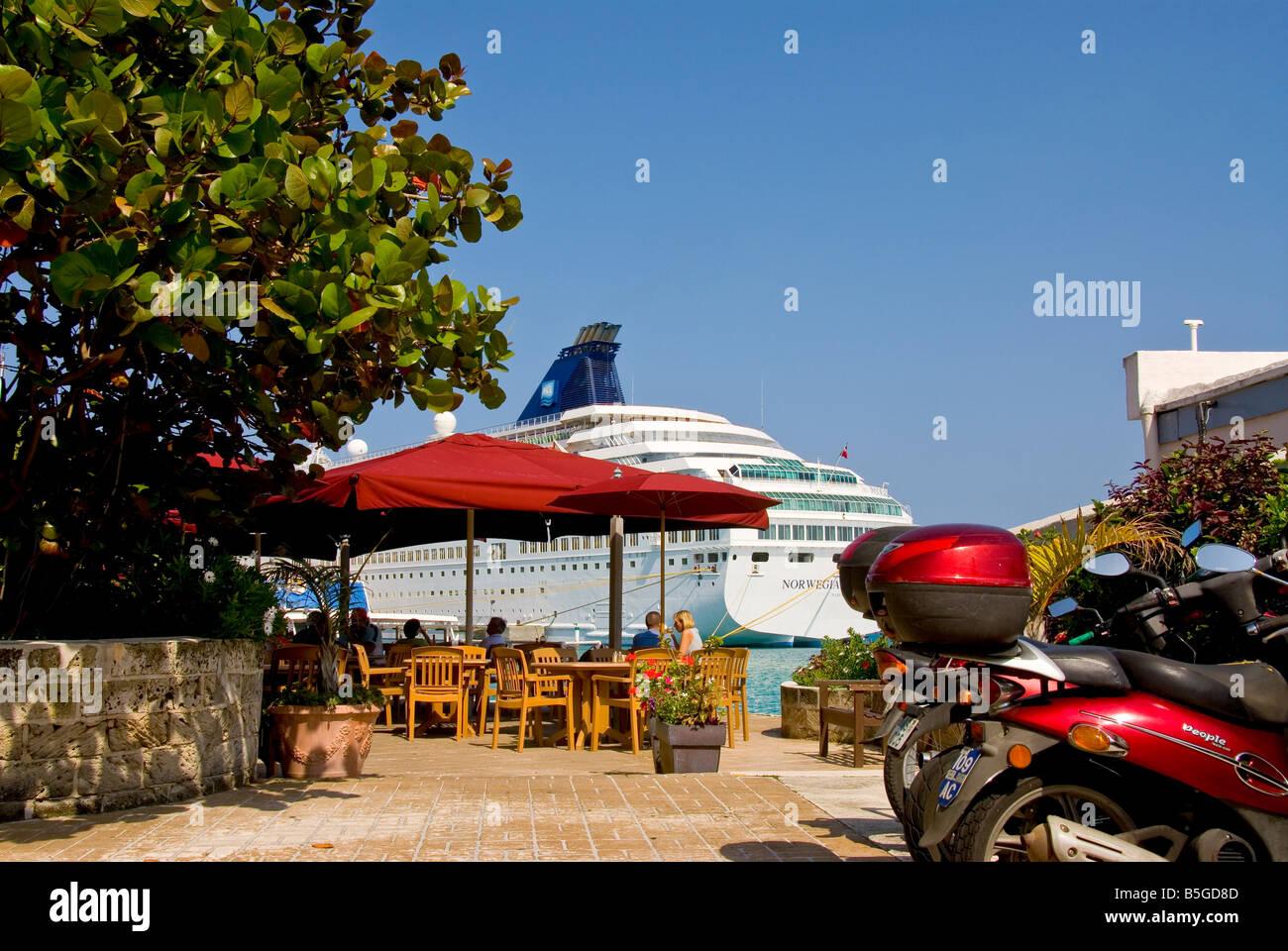 St George Bermudes coin coupé à l'oudoor cafe avec un parapluie rouge et navire de croisière en backgroud cyclomoteur rouge Banque D'Images
