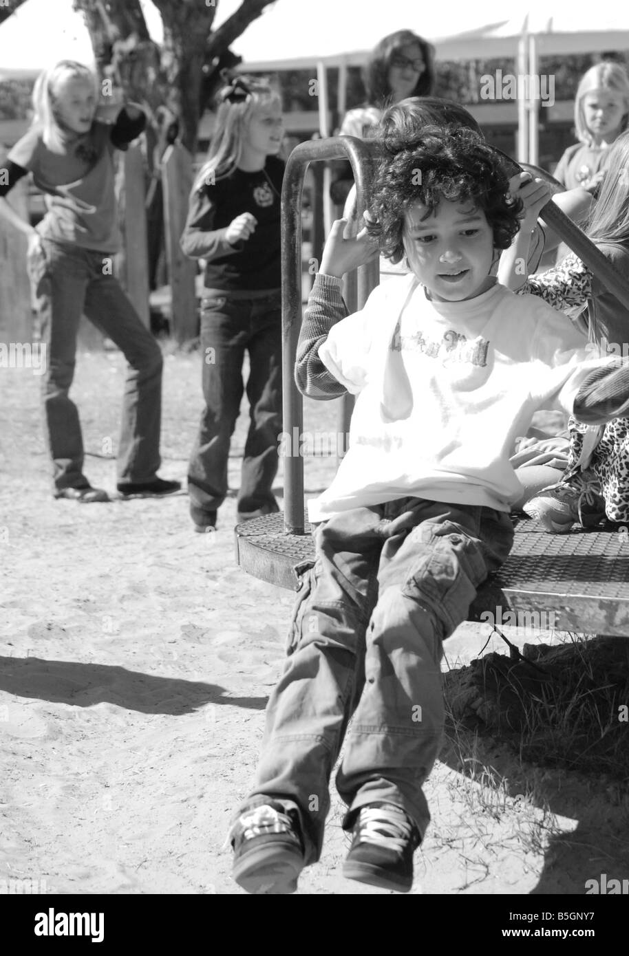 Image en noir et blanc d'un petit garçon jouant sur un manège sur une aire de jeux Banque D'Images