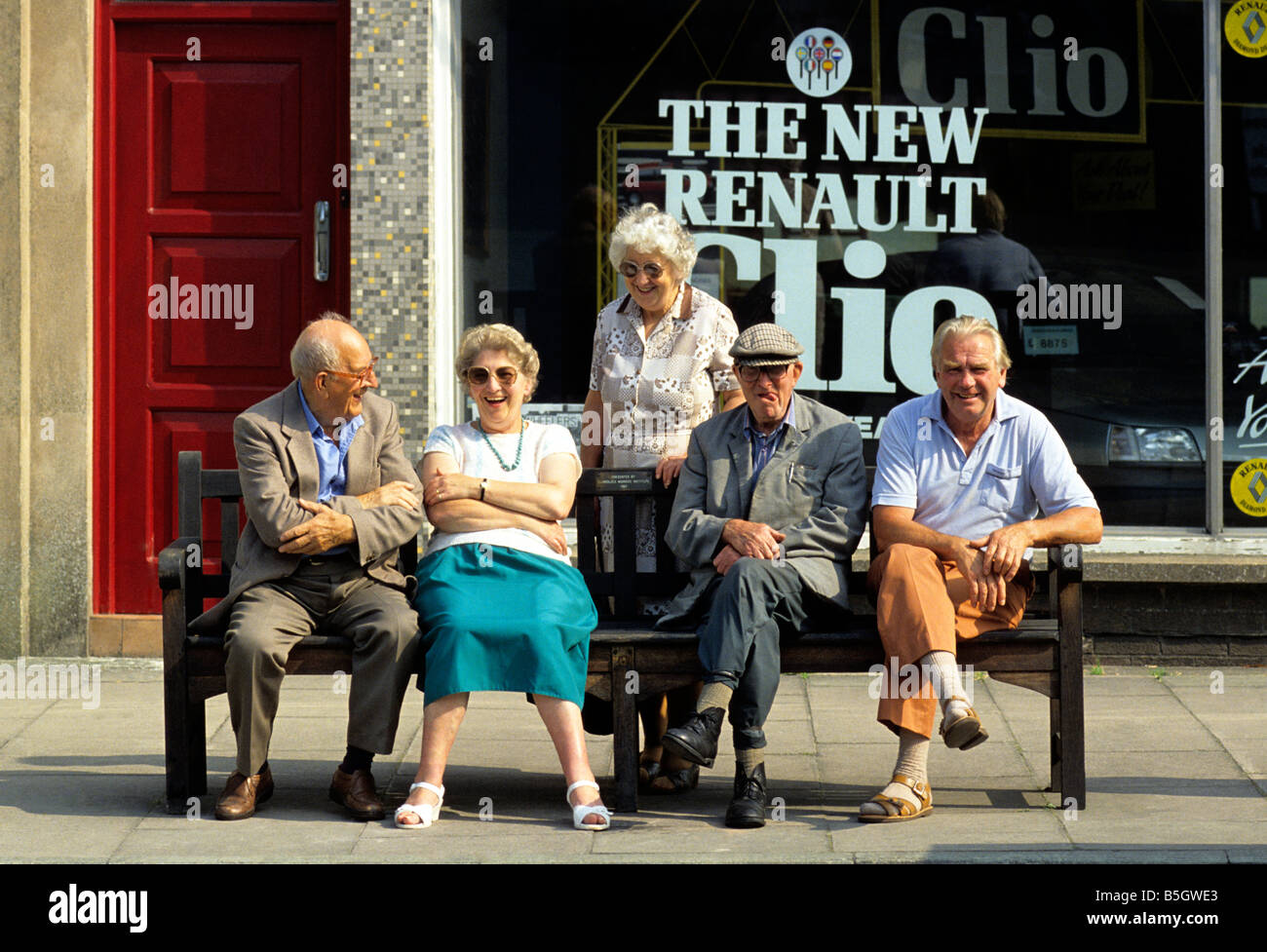 Groupe de retraités sur le banc de la rue à discuter ensemble - pays de Galles, Royaume-Uni. Banque D'Images