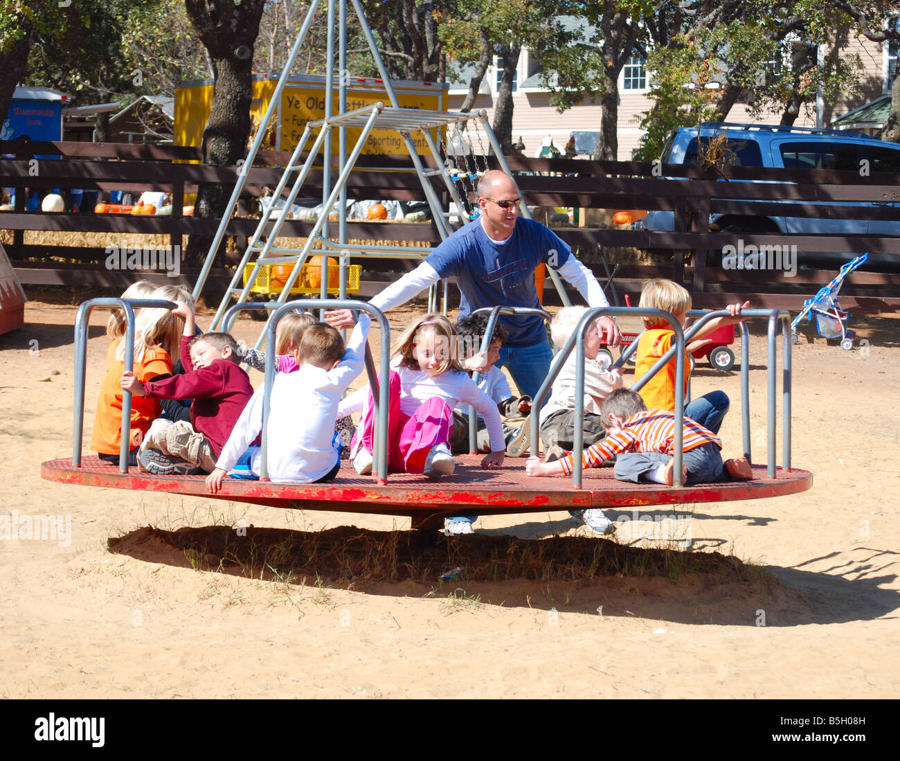 Père poussant les enfants sur un manège à une aire de jeux Banque D'Images