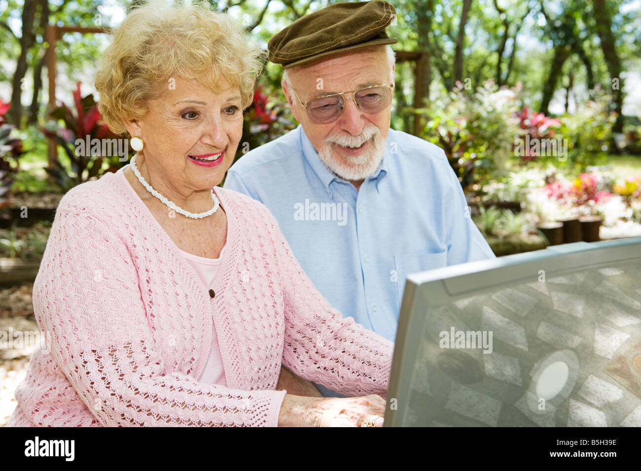 Happy senior couple sur leur ordinateur portable dans un beau cadre extérieur Banque D'Images