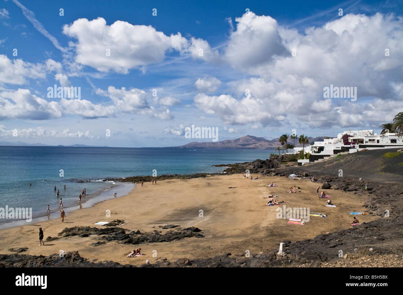 Dh Beach PUERTO DEL CARMEN LANZAROTE baigneurs sur la plage de sable de petites pierres de lave Banque D'Images