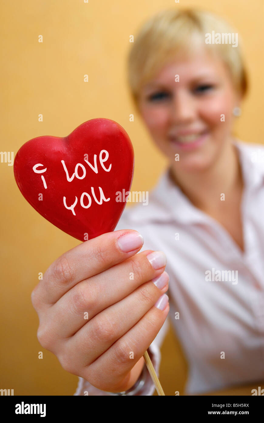 Jeune femme avec un coeur dans sa main 'J'aime'. Banque D'Images