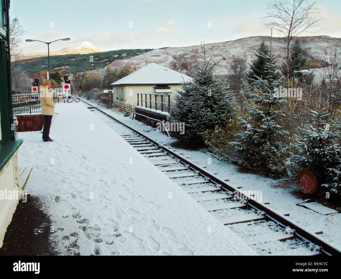 Un passager seul attend pour prendre le train tôt. Tôt le matin, neige à la gare de Crianlarich. Écosse Banque D'Images