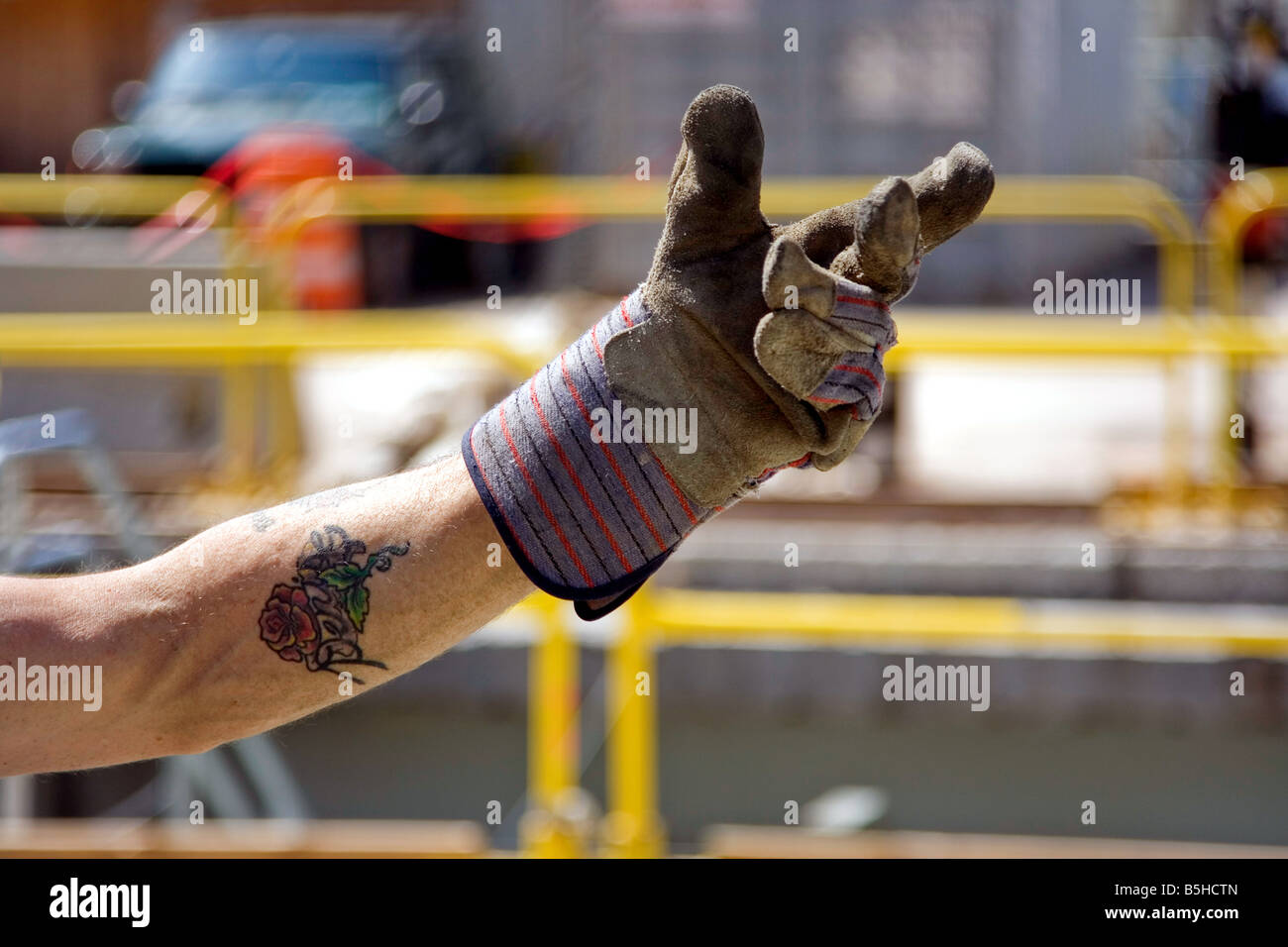 Un entrepreneur s main gantée en donnant un signal sur un arrière-plan flou d'une construction site Banque D'Images