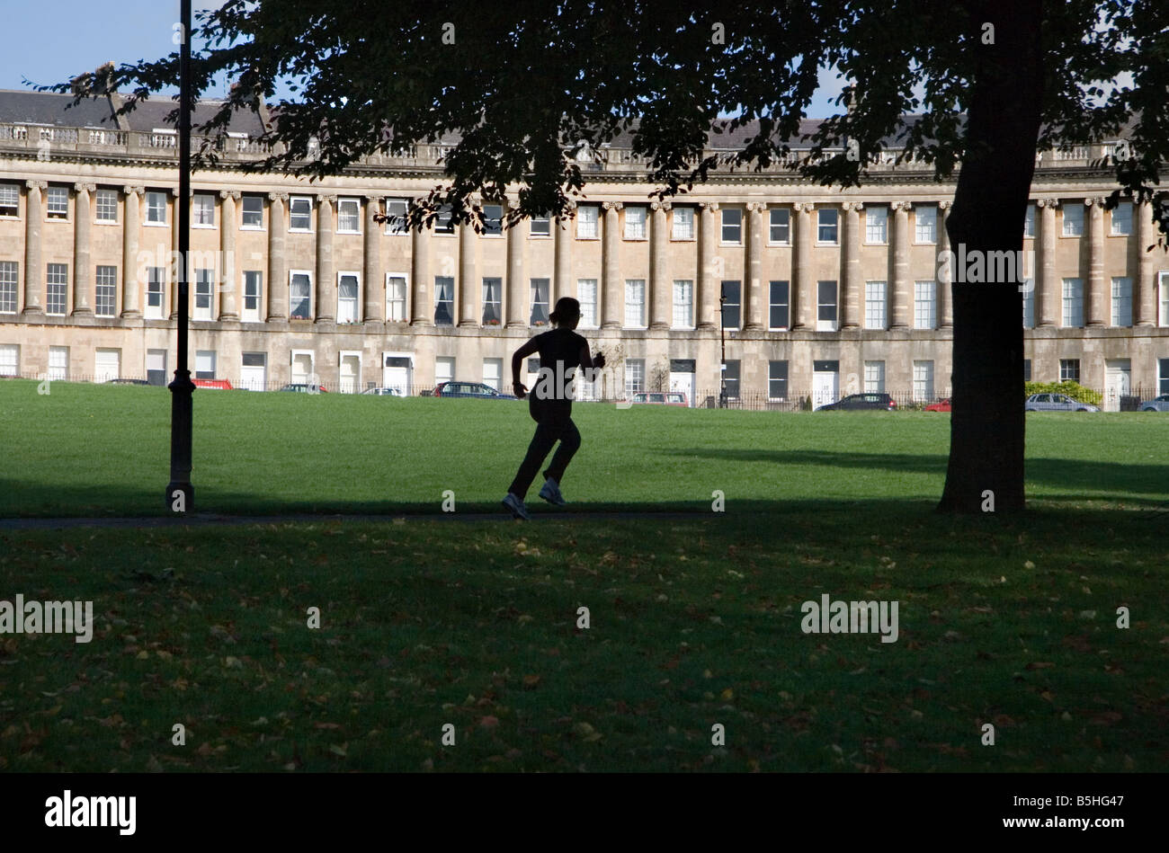 Un jogger s'exécutant sur un sentier en face du Royal Crescent, Bath, Somerset, Royaume-Uni Banque D'Images