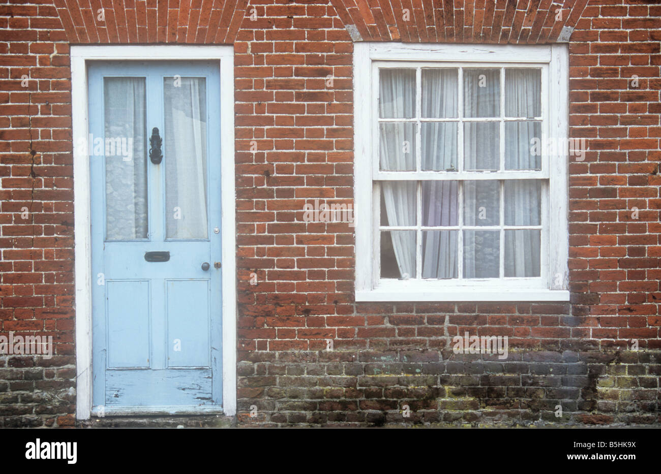 Une fois qu'élégant en bois et verre bleu pâle et blanc porte fenêtre à guillotine situé dans mur de brique rouge de terrasse chambre maintenant nécessitant une réparation Banque D'Images