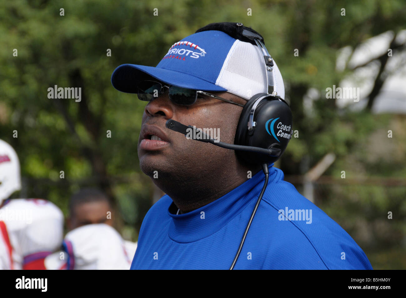 Coach en donnant des instructions sur un casque au cours d'un match de football à l'école secondaire agréable siège Banque D'Images