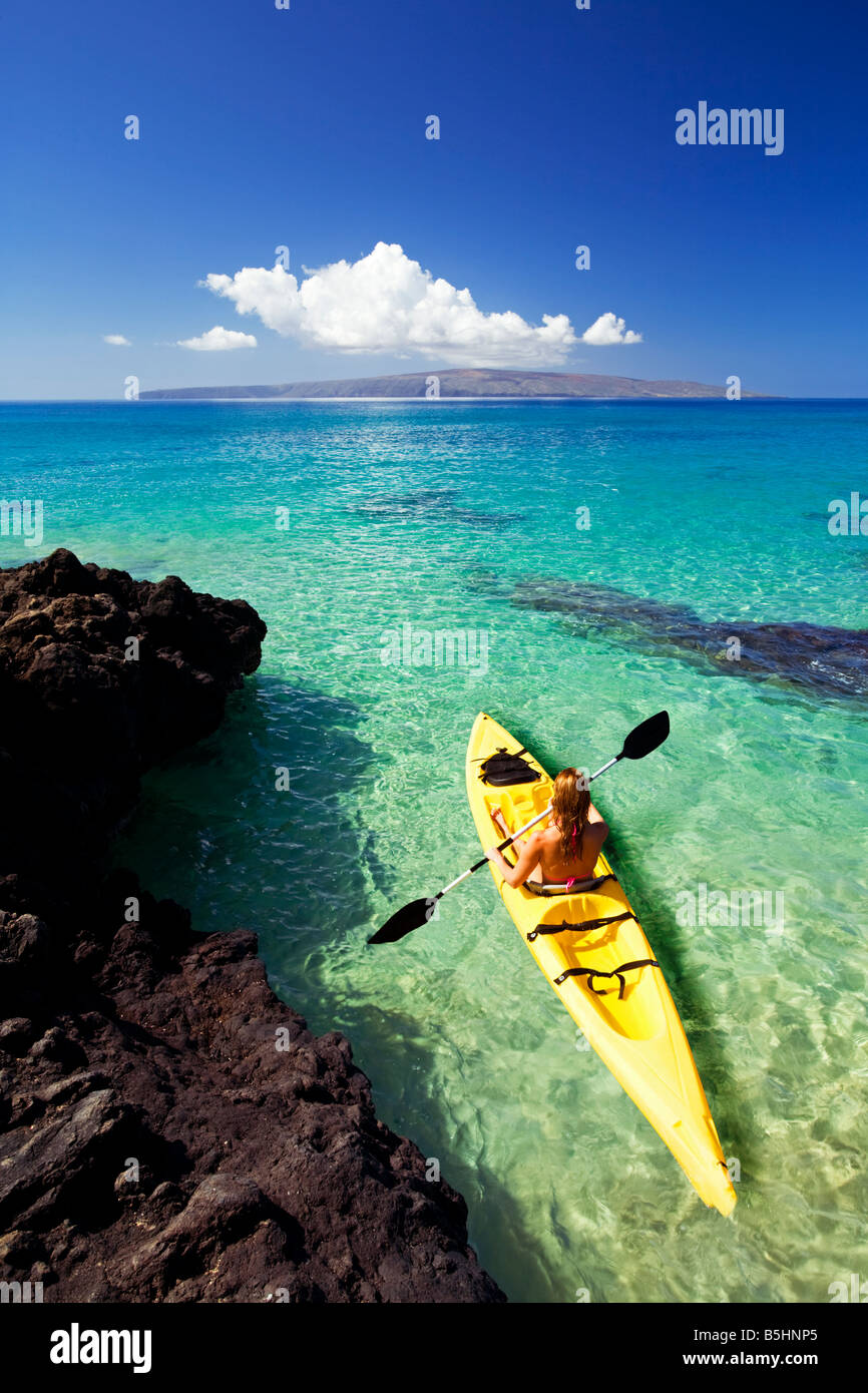 Une jeune femme des pagaies kayak jaune à Makena, Maui, Hawaii. Banque D'Images