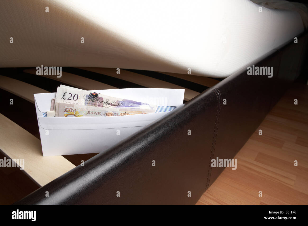 Liasse de 20 et 10 livres sterling en espèces de la banque d'Angleterre dans une enveloppe sous le matelas en peluche d'un lit Banque D'Images