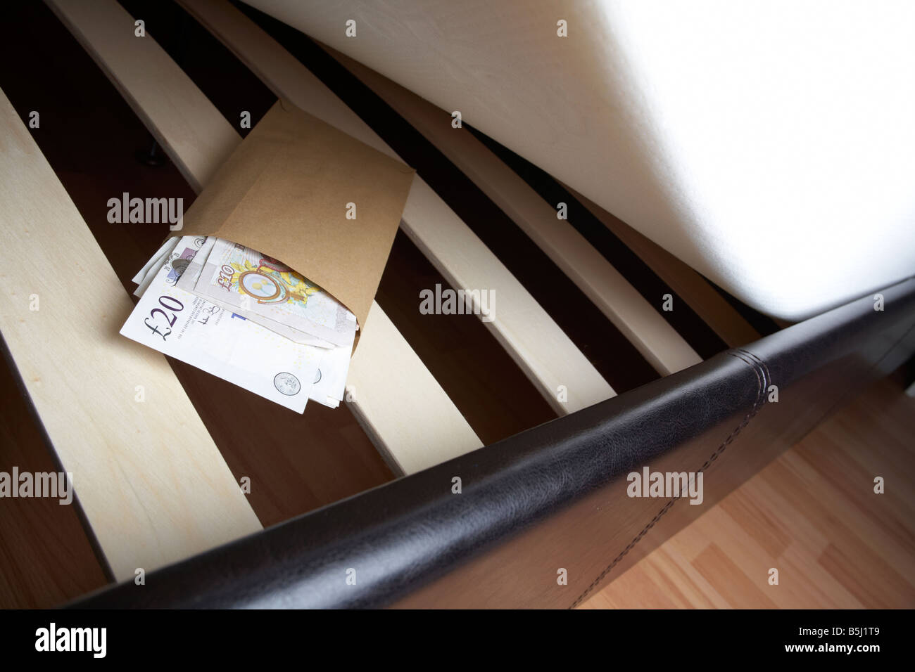 Liasse de 20 et 10 livres sterling en espèces de la banque d'Angleterre dans une enveloppe sous le matelas en peluche d'un lit Banque D'Images