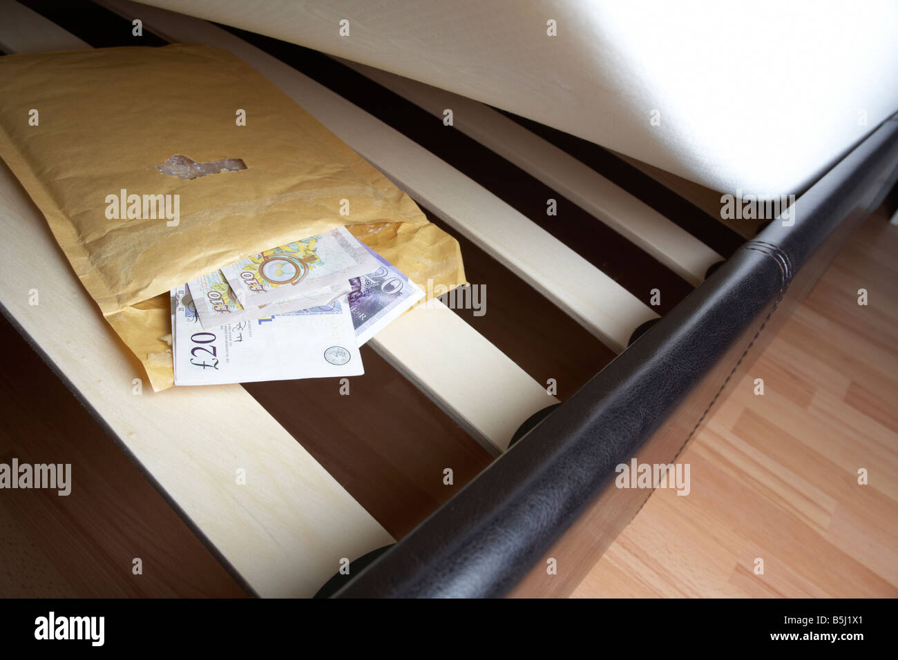 Liasse de 20 et 10 livres sterling en espèces de la banque d'Angleterre dans une enveloppe sous le matelas en peluche d'un lit pour les économies possibles ou l'évasion fiscale Banque D'Images