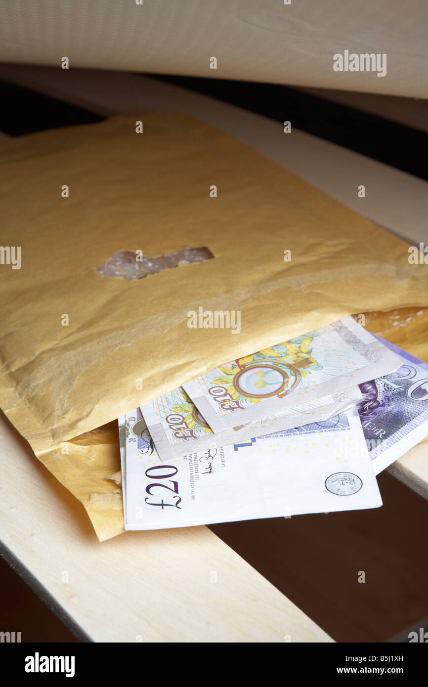 Liasse de 20 et 10 livres sterling en espèces de la banque d'Angleterre dans une enveloppe sous le matelas en peluche d'un lit Banque D'Images