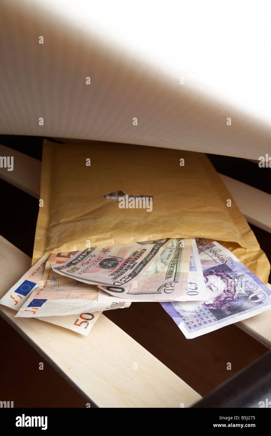 Wad mixte de service de livres sterling Euros et dollars en espèces dans une enveloppe sous le matelas en peluche d'un lit que l'épargne en cas d'une crise bancaire Banque D'Images