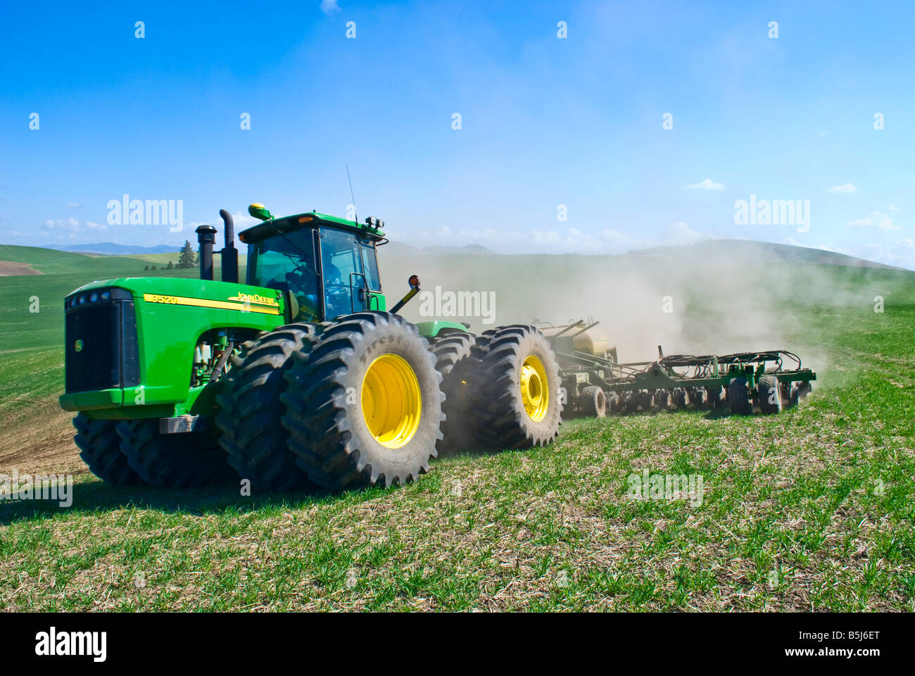 Un tracteur tire un semoir pneumatique à replanter le blé d'hiver endommagé par la neige au printemps dans la région de Washington Palouse Banque D'Images